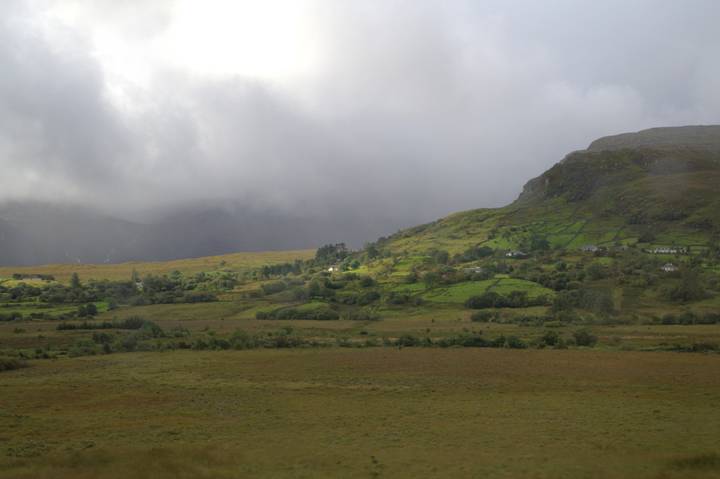 Misty Irish valley with patchwork farmland leading to a cloud-covered mountain ridge.