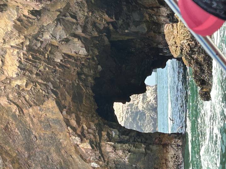 Rocky sea arch with choppy ocean water visible through the opening.
