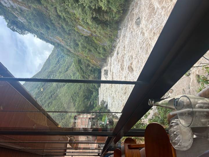View through a restaurant window of a fast-flowing river and lush canyon walls.