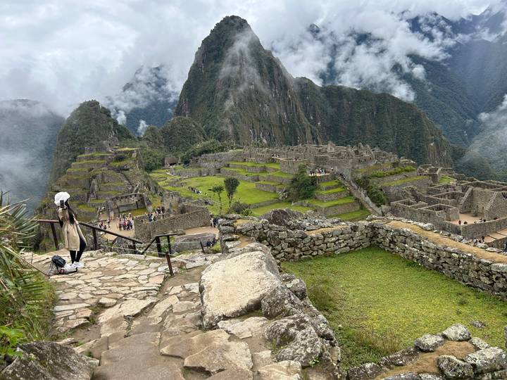 Visitors overlook terraced ruins of Machu Picchu immersed in drifting clouds.