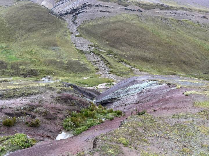 Close view of multicolored earth and small ravines on a high Andean slope.