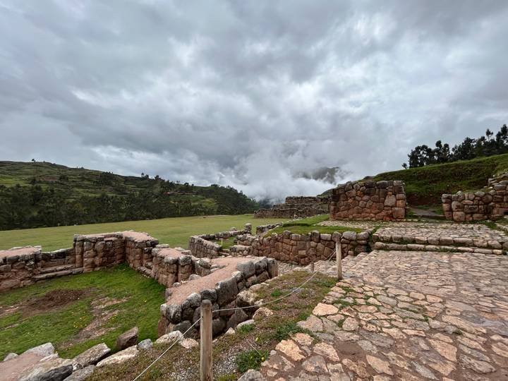 Stone terraces and pathways of a high-altitude Inca site set against misty hills.