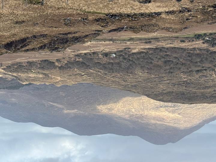 Expansive moorland and rolling hills illuminated by patchy sunlight along the Ring of Kerry.
