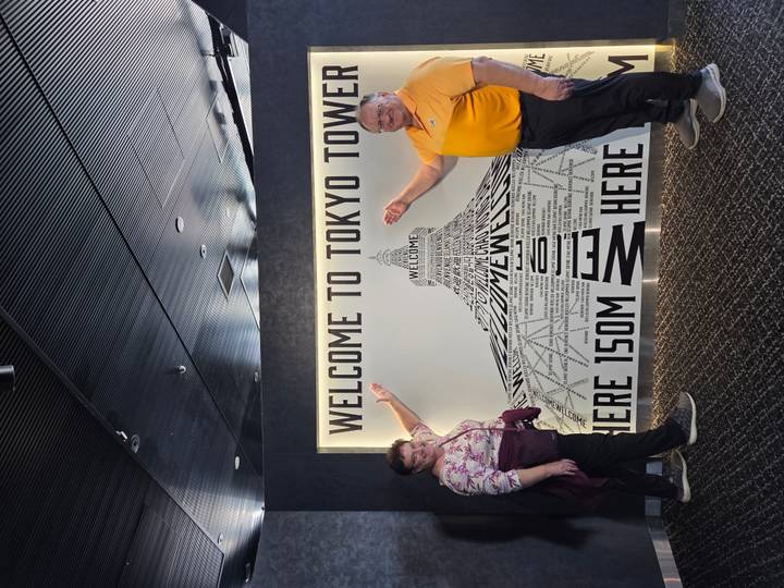 Visitors happily point to a lit ‘Welcome to Tokyo Tower’ sign inside an observation deck.