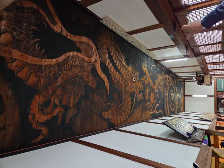 Wooden ceiling panel painted with an enormous traditional dragon motif inside a Japanese temple hall.