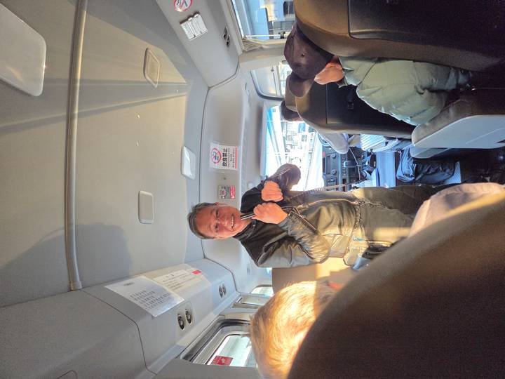 Tour guide enthusiastically giving information to passengers inside a small tour minibus.