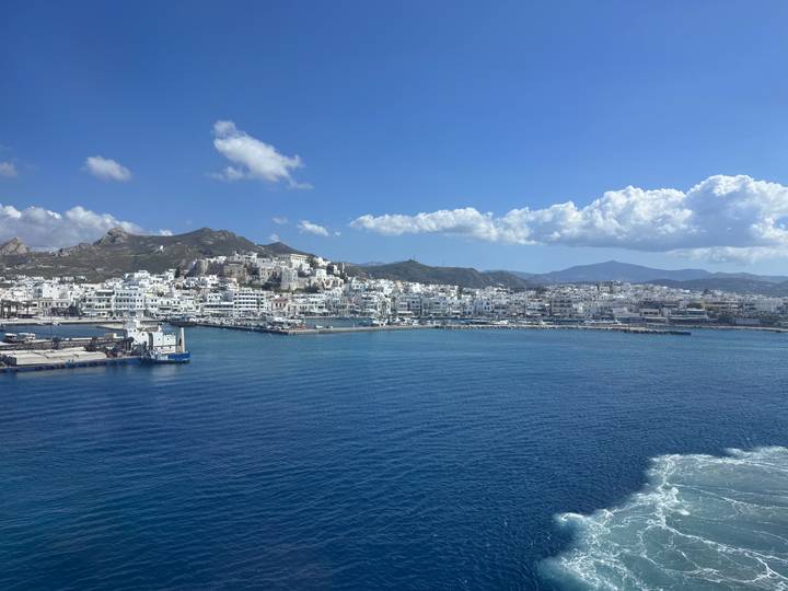 Panoramic coastal town with whitewashed buildings hugging the shoreline of deep blue sea.