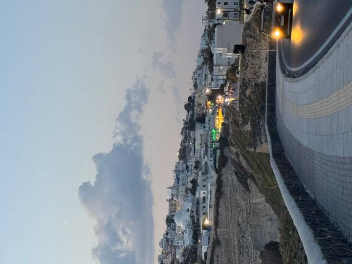 Winding cliff-top road overlooking Santorini’s villages as evening light fades.