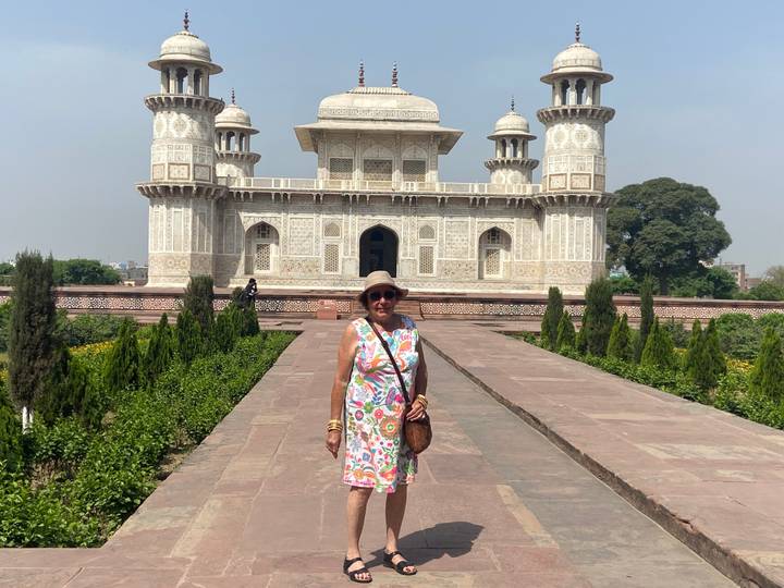 Woman posing on the pathway leading to the Baby Taj mausoleum in Agra under bright midday sun.