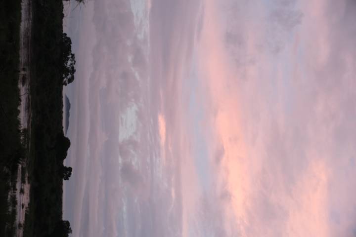 Soft pink and purple sunset sky over a river and distant trees in the savannah.