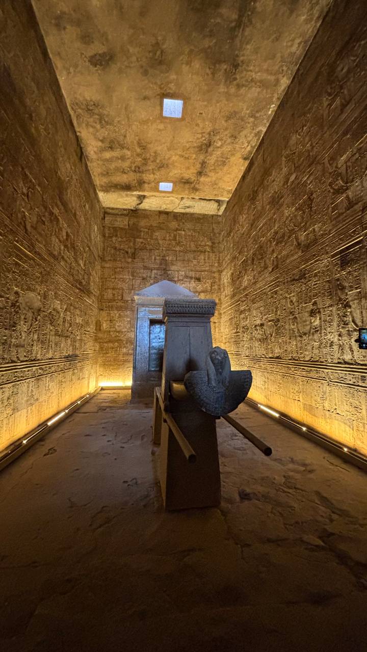 Dimly lit inner chamber of an Egyptian temple featuring a stone barque shrine