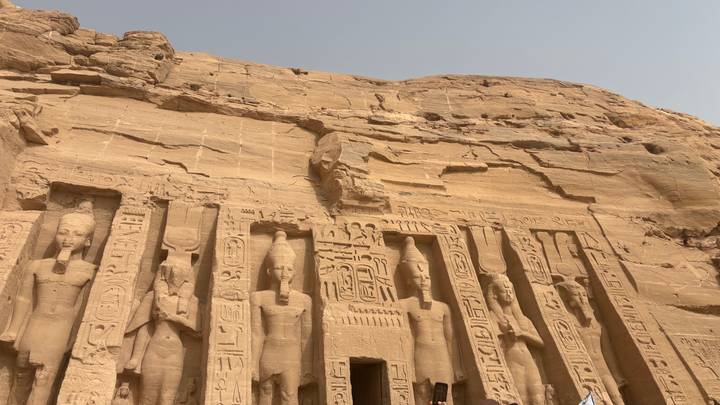 Close-up of the rock-cut statues and hieroglyphs on Abu Simbel temple façade under a pale sky
