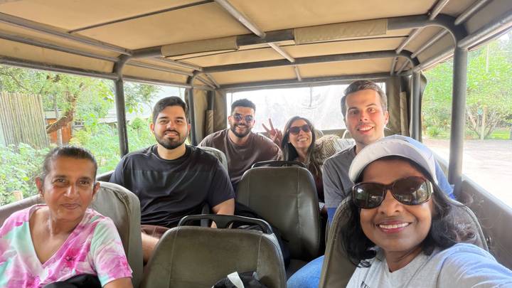 Smiling safari group taking a selfie inside an open game-drive vehicle.
