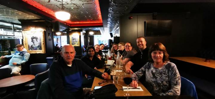 Tour group gathered around a pub table enjoying drinks in a dimly lit bar interior.