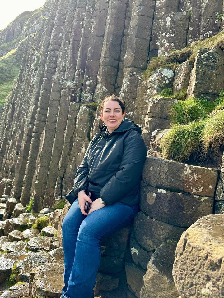 Woman sitting on the famous hexagonal basalt columns of the Giant's Causeway.