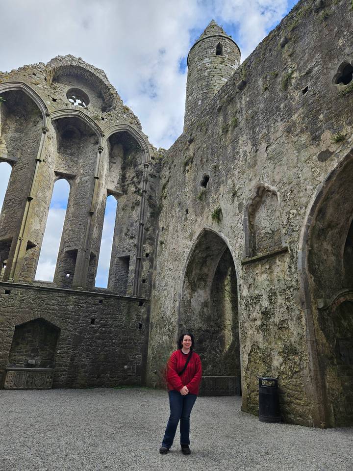 Weathered interior walls and tall narrow windows of an ancient cathedral ruin.