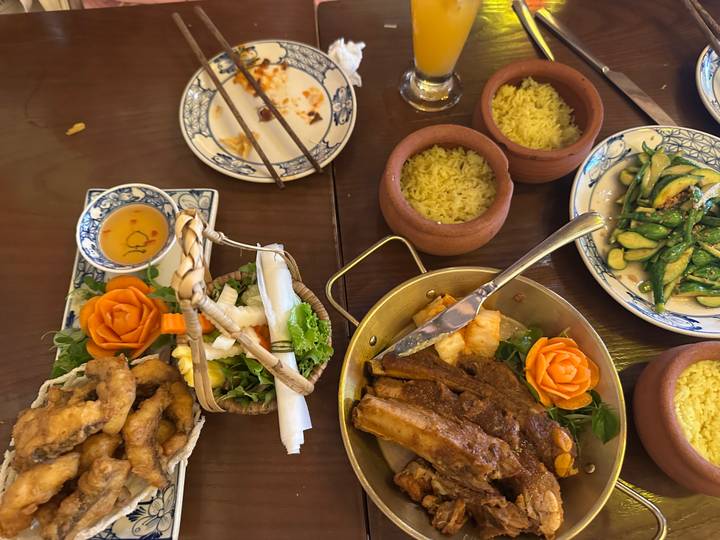 Colorful spread of Vietnamese dishes including clay-pot curry, rice and vegetables on a wooden table.