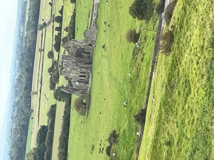 Aerial view of medieval stone ruin standing in rolling green farmland.