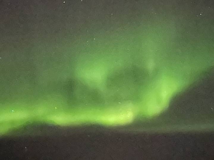 Faint, blurry green aurora glow across a dark night sky