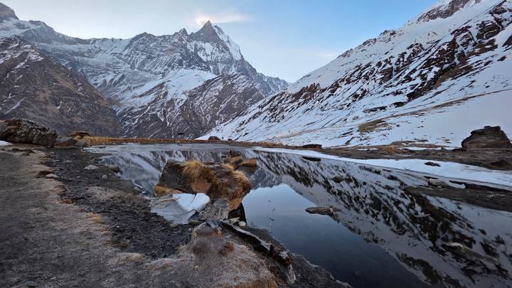 Snow-covered Himalaya peak reflecting perfectly in a still alpine pond at dawn