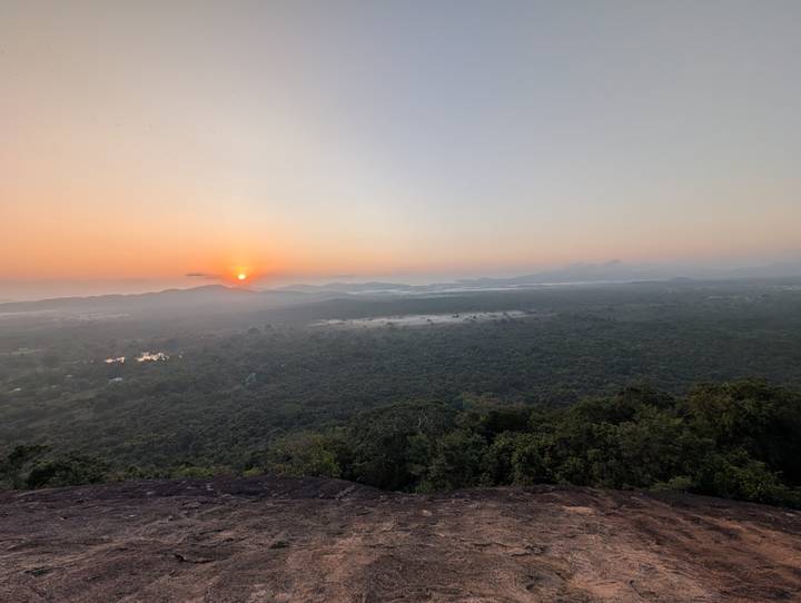 Broad vista of misty forest and rolling hills with the sun rising on the horizon