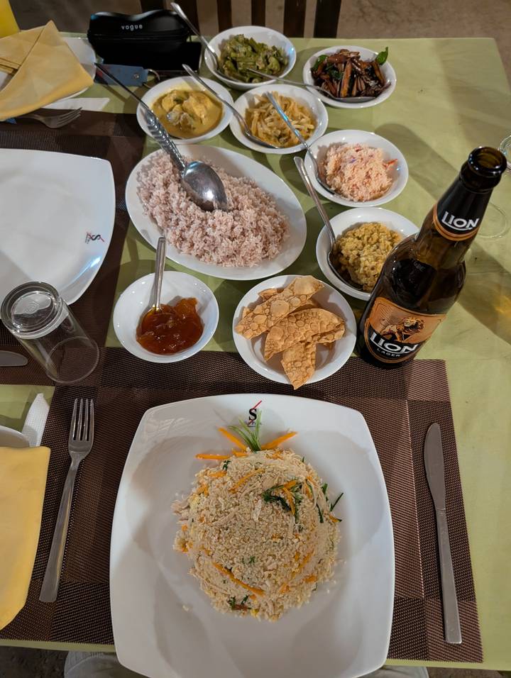 Traditional Sri Lankan meal with rice, curry, papad and Lion beer on a restaurant table