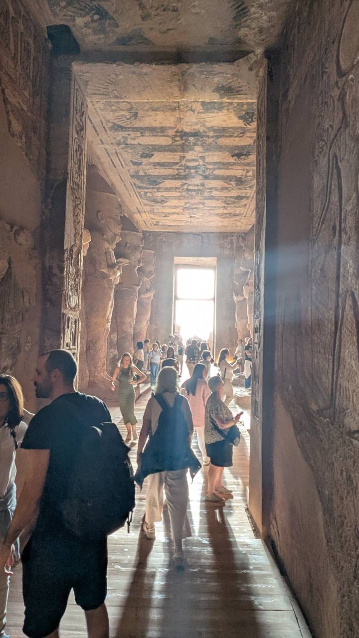 Crowded interior chamber of Abu Simbel temple with intense backlight streaming through the doorway.