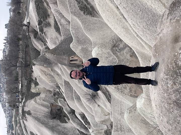 Traveler poses playfully on creamy rock formations of Cappadocia’s lunar landscape.