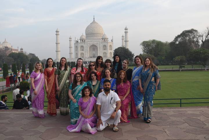 Group dressed in colorful saris posing in front of the Taj Mahal gardens
