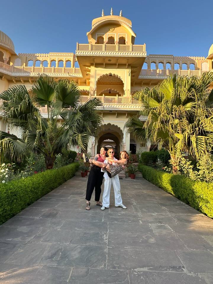Three friends posing playfully in the garden courtyard of a heritage Indian haveli.