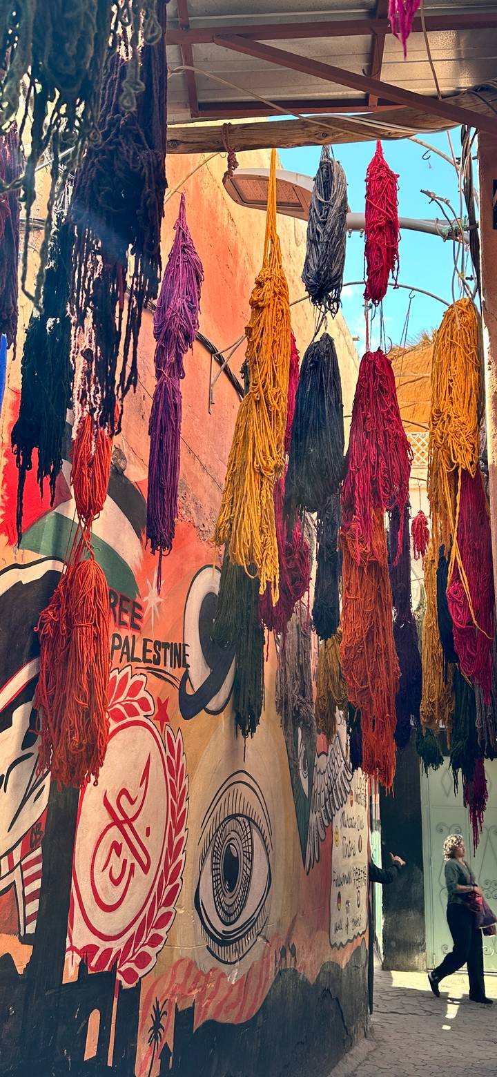 Hanks of brightly coloured wool hanging in a narrow Moroccan medina street.