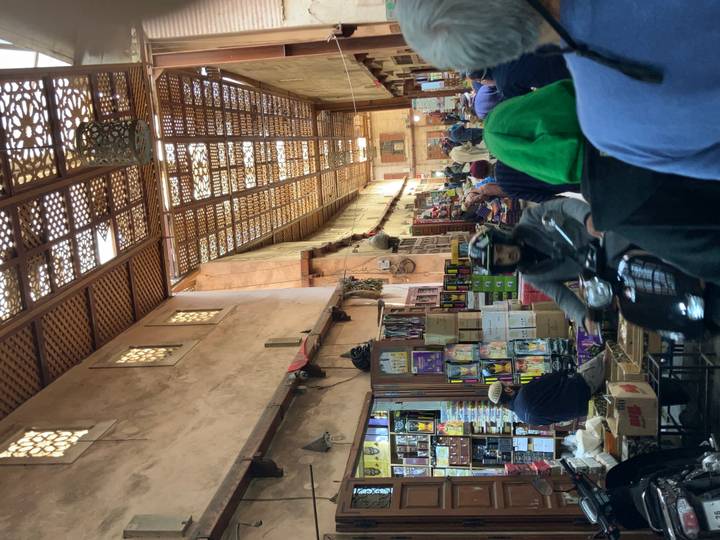 Bustling covered souk passage in Marrakesh filled with stalls, shoppers and passing motorbike.