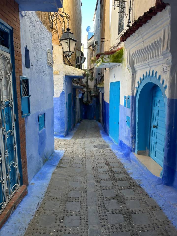 Narrow alley painted in varying shades of blue with arched doorway in Chefchaouen.