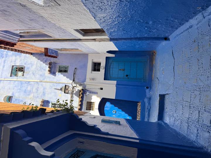 Narrow alleyway of vivid blue-painted houses and carved doors in Chefchaouen’s medina.