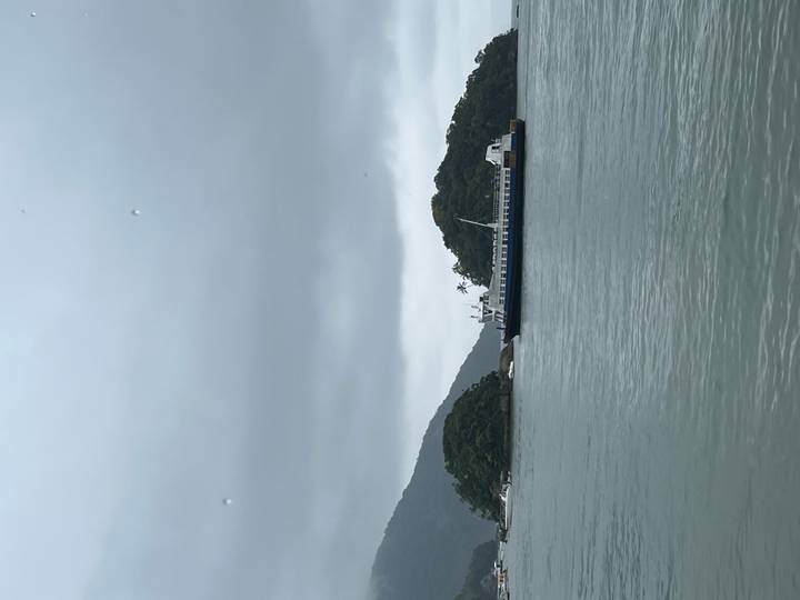 Passenger ferry cruising between lush green islands on an overcast day.