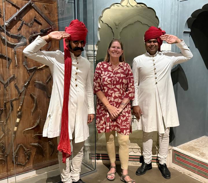 Traveller posing with two uniformed guards wearing traditional turbans indoors.