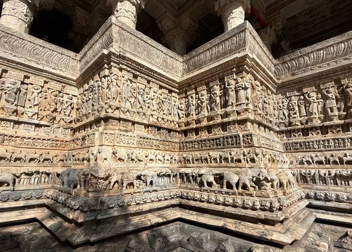 Elaborately carved stone panels depicting deities, dancers and animals on a temple wall.