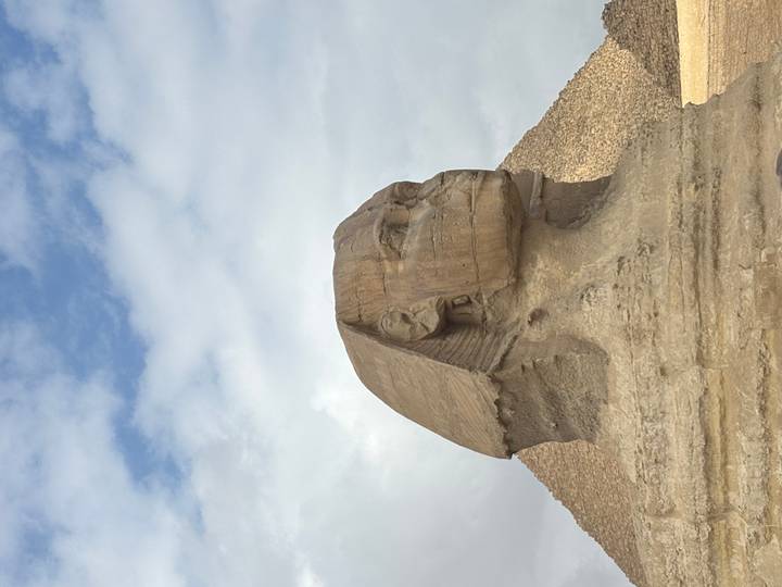 Side profile of the Great Sphinx with the Pyramid of Khafre in the background.
