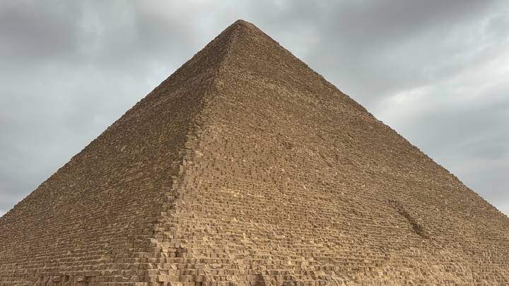 Close-angle view of the Great Pyramid's limestone blocks rising sharply into the sky.