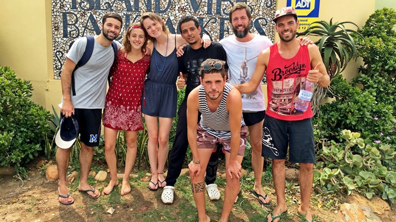 Group of people posing barefoot by a sign.