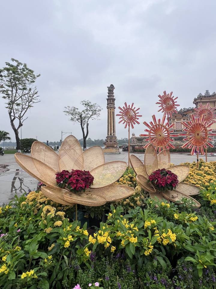 Decorative floral installations and traditional column in a public square on a grey day in Hue.