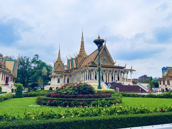 Ornate Royal Palace complex in Phnom Penh surrounded by lush gardens under a bright sky.