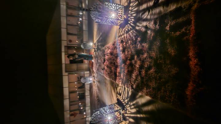 Night shot of lantern-lit carpeted pathway leading to luxury desert tent, motion blur present.