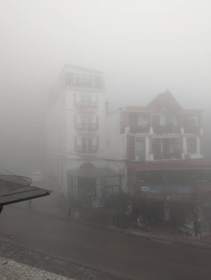 Tall white hotel facade barely visible through dense mountain fog