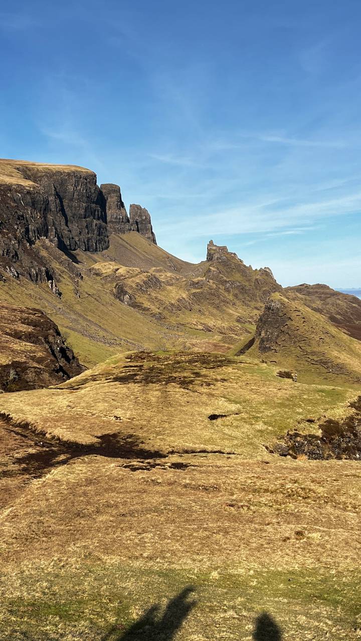 Rugged, jagged peaks and grassy ridges of the Quiraing landscape glow under bright Highland sun.