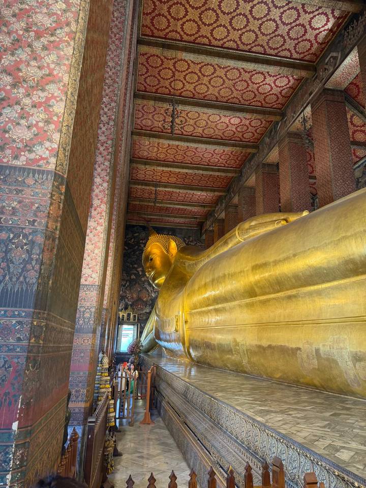 Golden reclining Buddha statue inside an ornately decorated temple hall