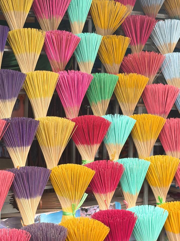 Colorful bundles of incense sticks neatly arranged in rows creating a vibrant pattern