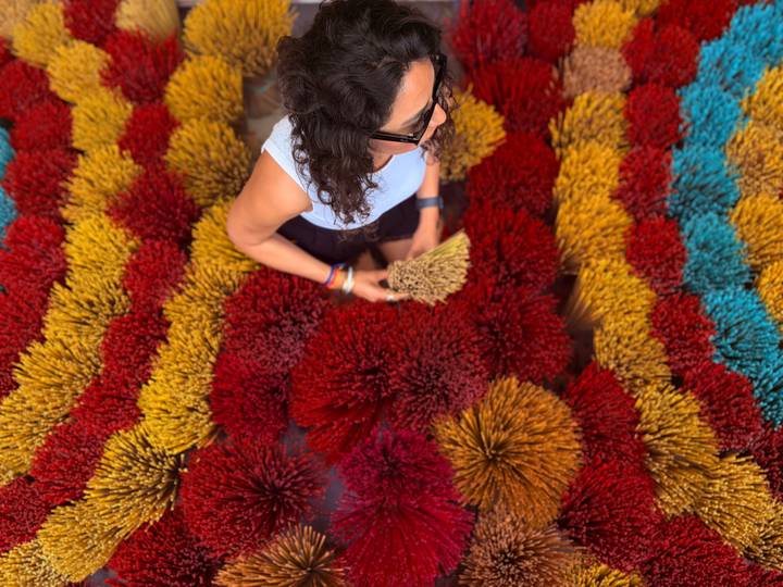 Overhead shot of woman selecting bunches of colorful incense sticks arranged in vibrant patterns