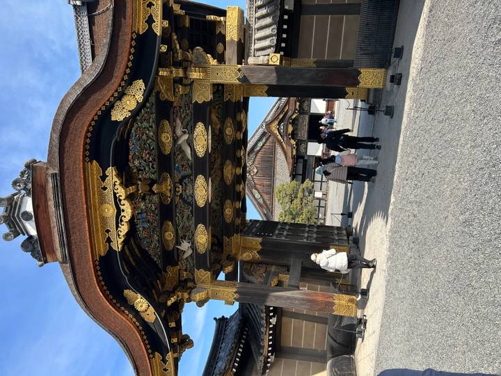 Ornately decorated wooden gate at Kyoto’s Nijo Castle with visitors walking beneath.