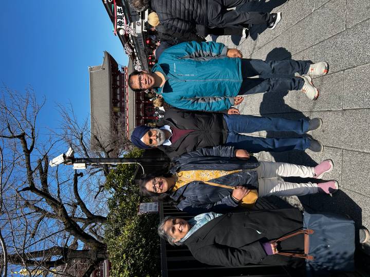 Family group stands on the approach to Tokyo’s Senso-ji temple with pagoda roof behind.